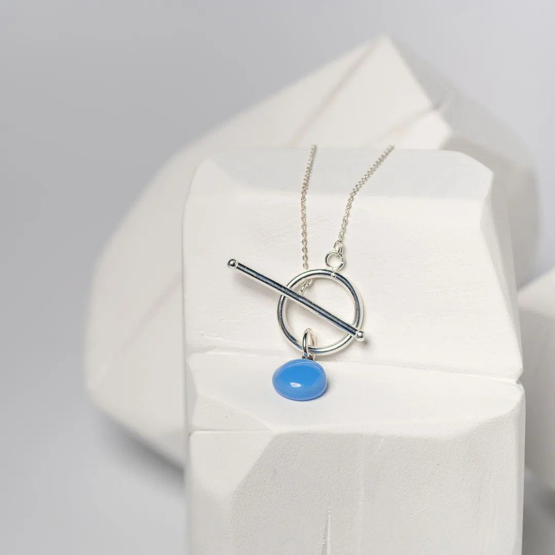 Collier argenté et pendentif bleu posés sur un bloc de plâtre