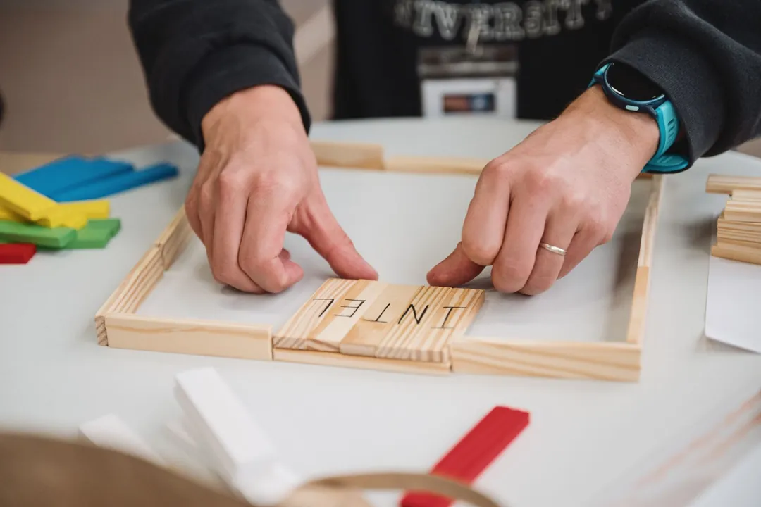 Deux mains assemblent des pièces de bois sur une table