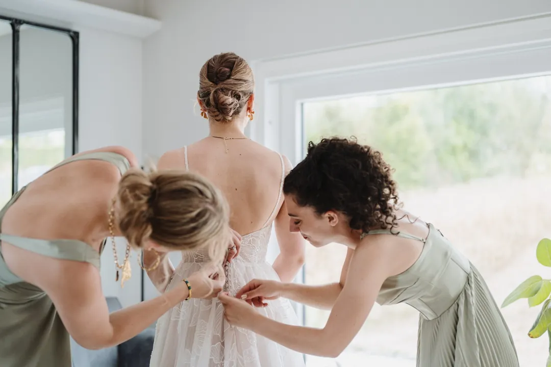 Deux témoins ferment la robe de la mariée