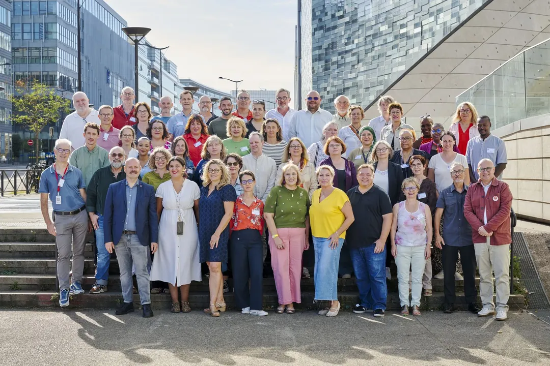 Grande photo de groupe sur des marches, immeubles de bureaux en arrière-plan