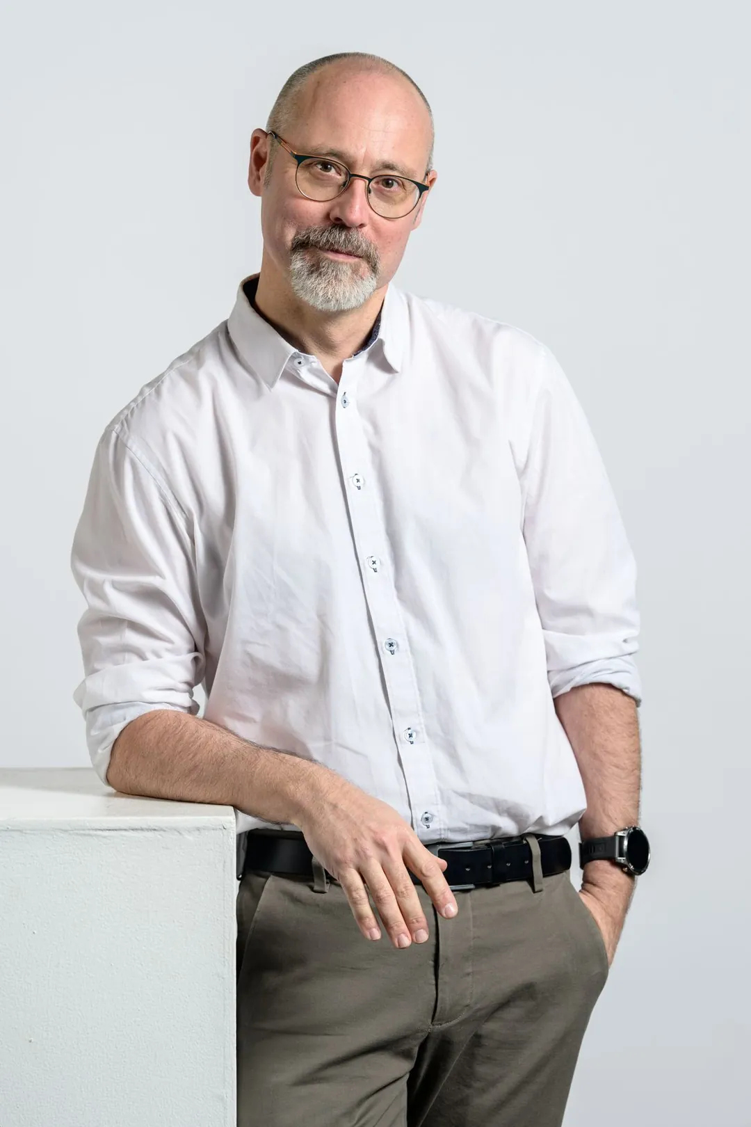 Jean-Christophe Piot en chemise blanche, appuyé sur un cube blanc