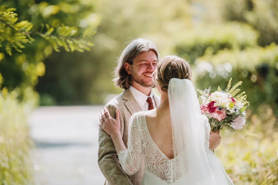 Les mariés rient dans un jardin, bouquet à la main