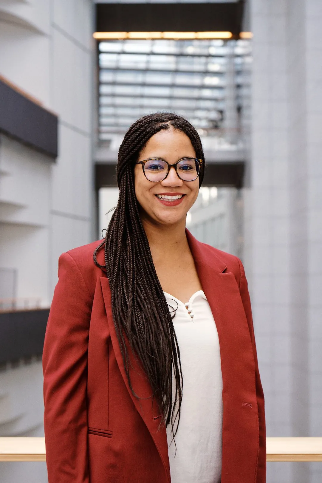 Mélissa Camara, souriante, en veste rouge dans un atrium