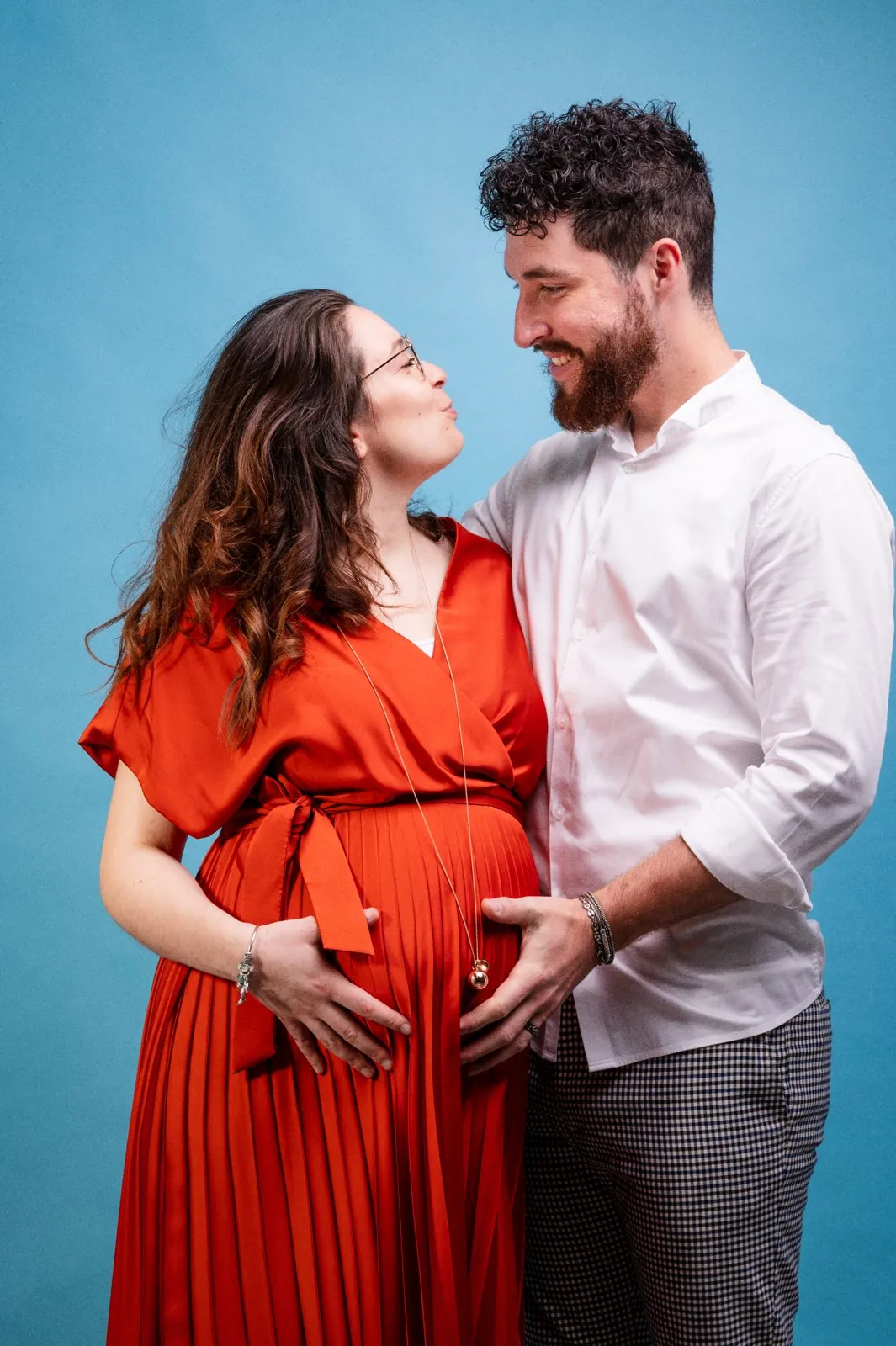 Portrait de couple pendant la grossesse, sur fond bleu