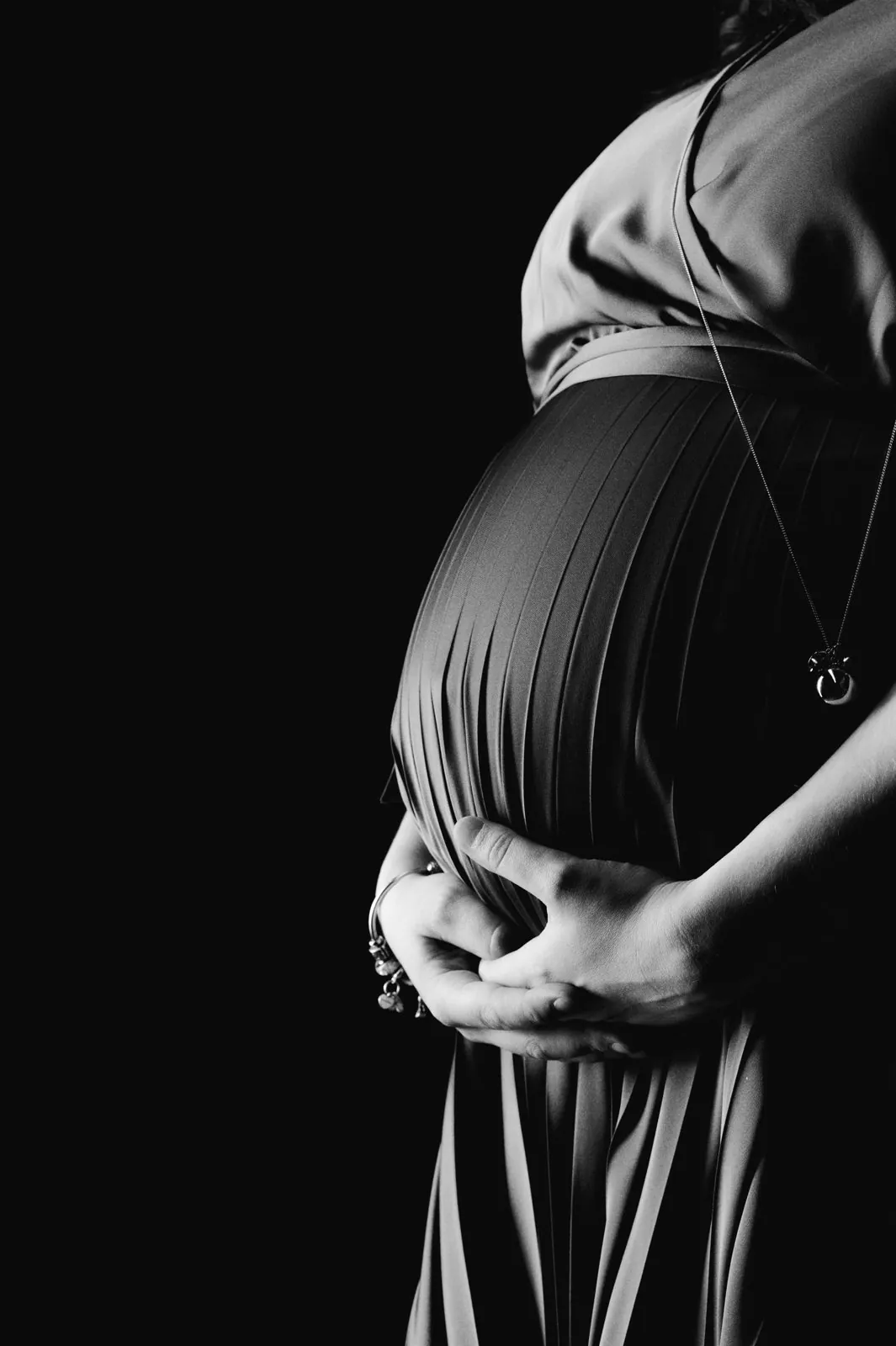 Portrait de grossesse en noir et blanc, mains sur le ventre
