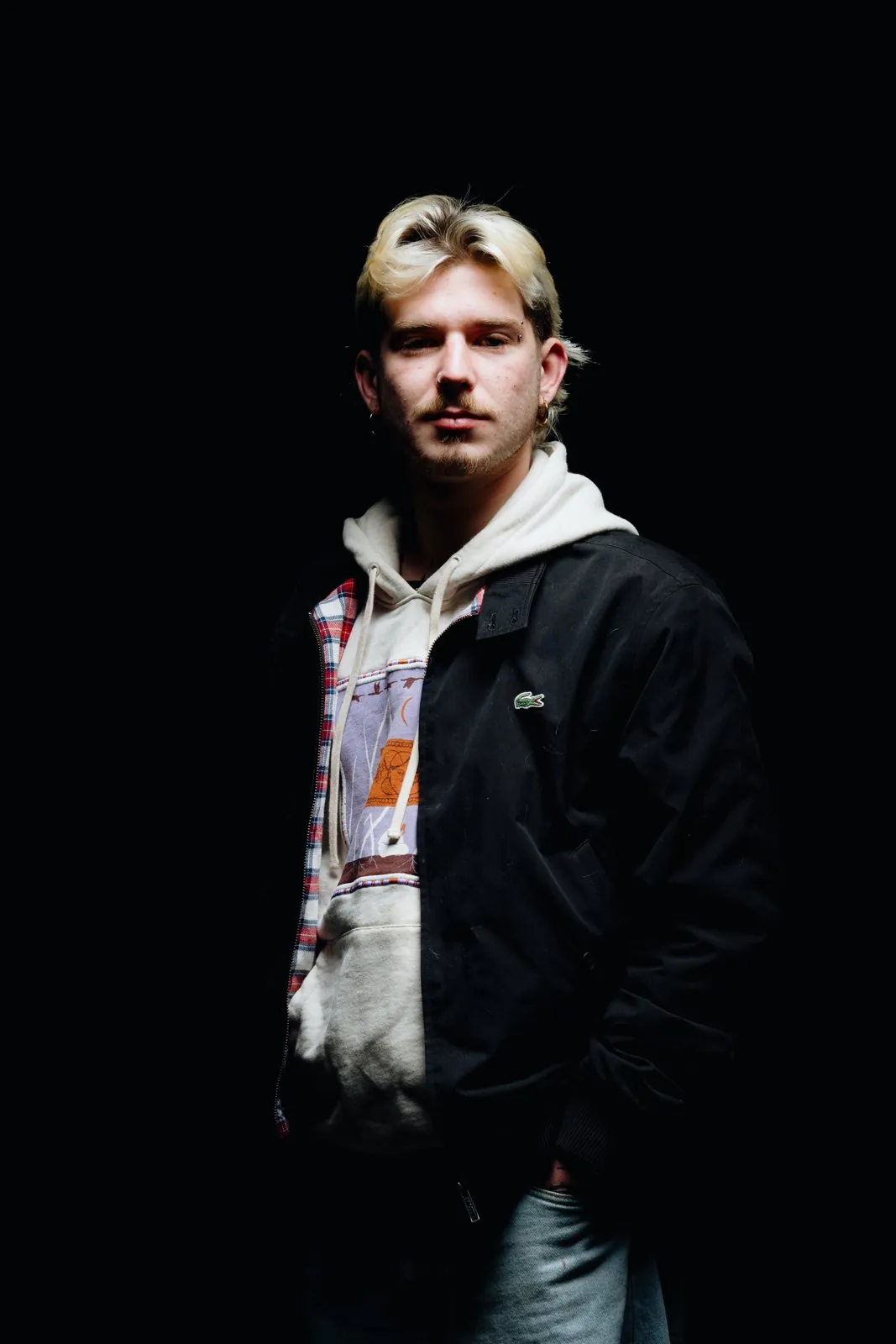Portrait en studio sur fond noir, un jeune homme en veste