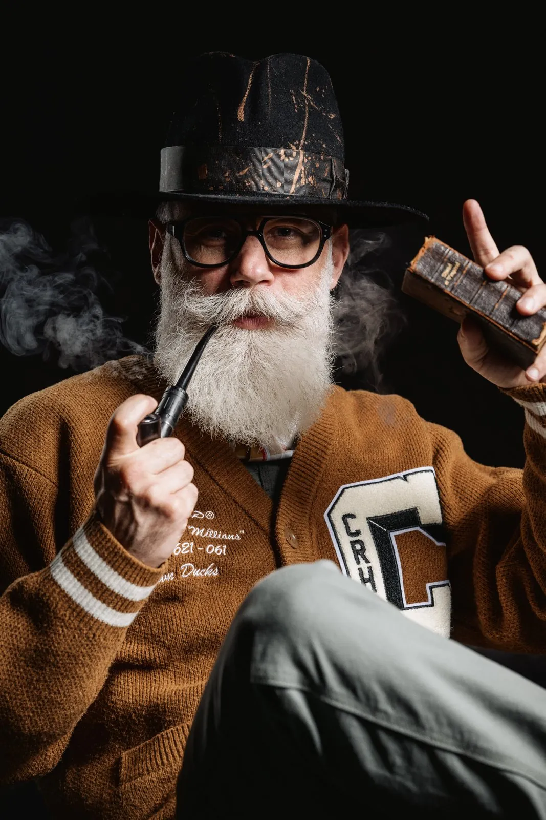 Portrait en studio, un homme barbu en chapeau fume la pipe