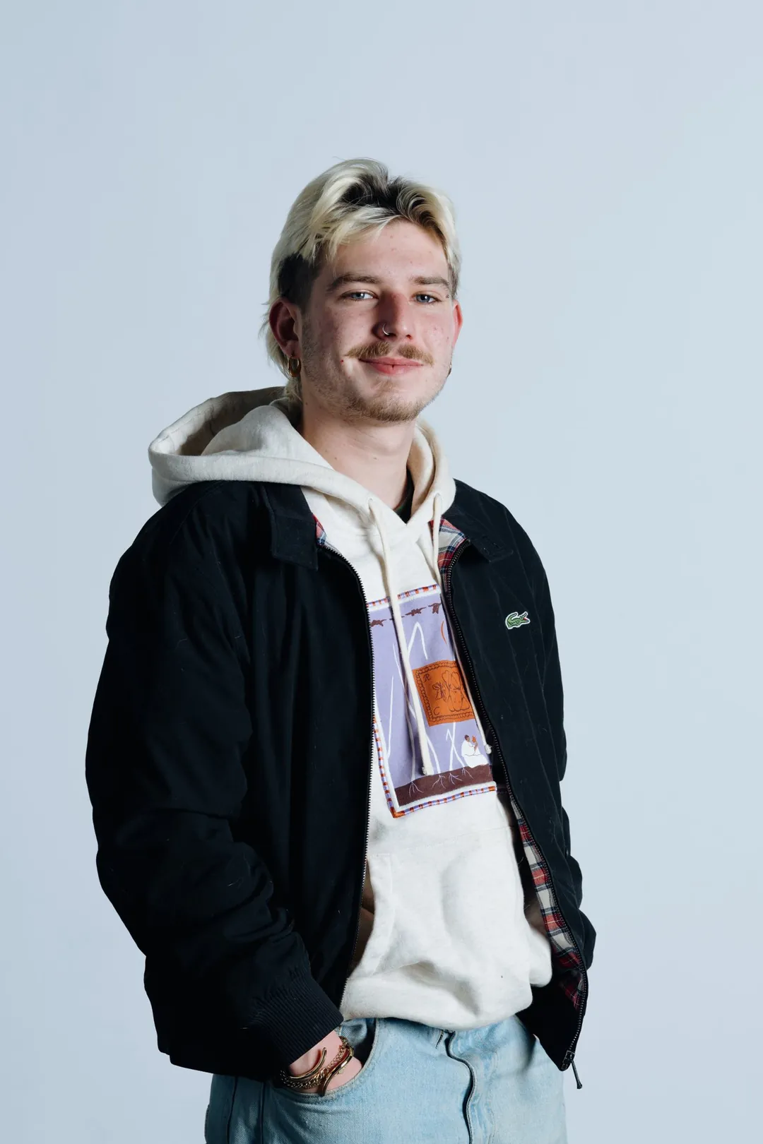 Portrait en studio sur fond clair, un jeune homme sourit