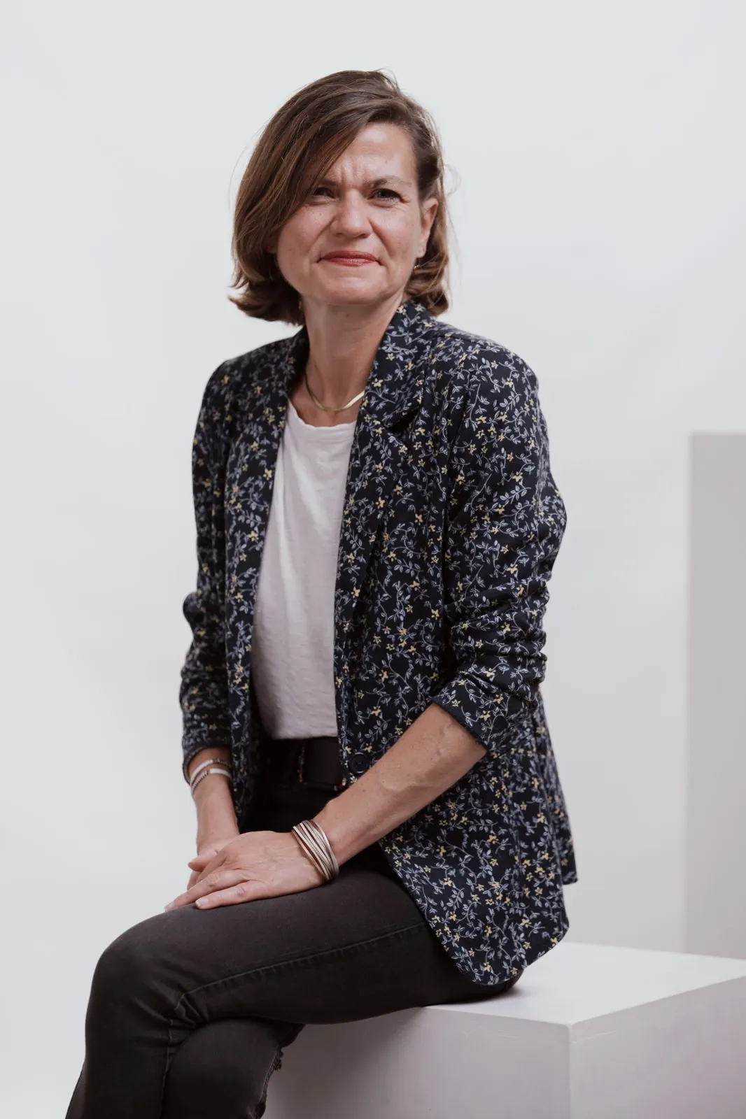 Portrait en studio, une femme assise sur un cube blanc