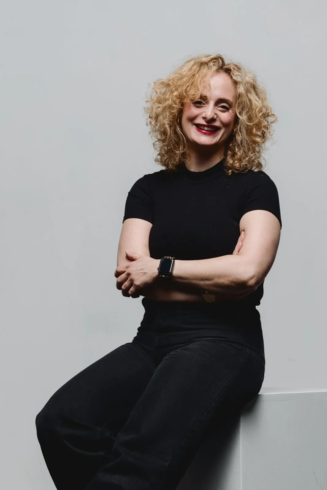 Portrait en studio, une femme aux cheveux bouclés, bras croisés
