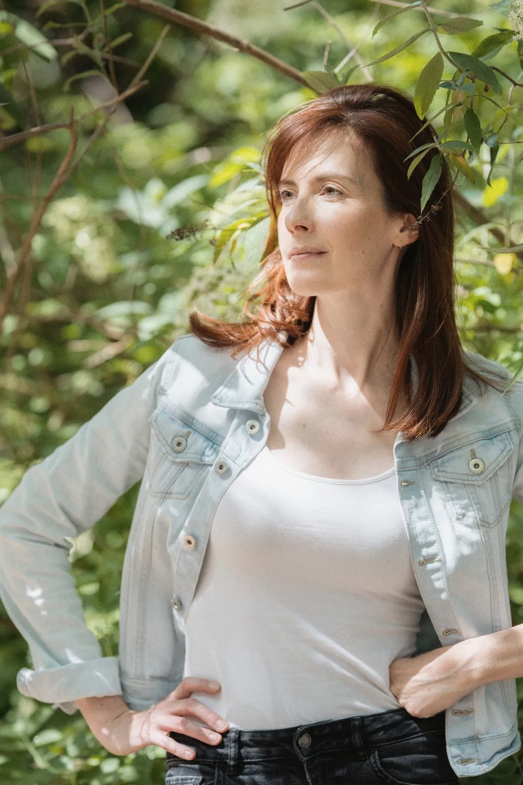 Portrait en ville, une femme en veste en jean dans la verdure