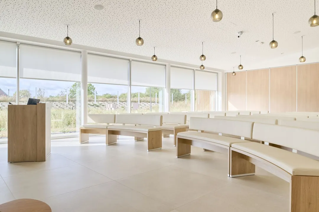 Salle de cérémonie baignée de lumière naturelle, bancs de bois clair