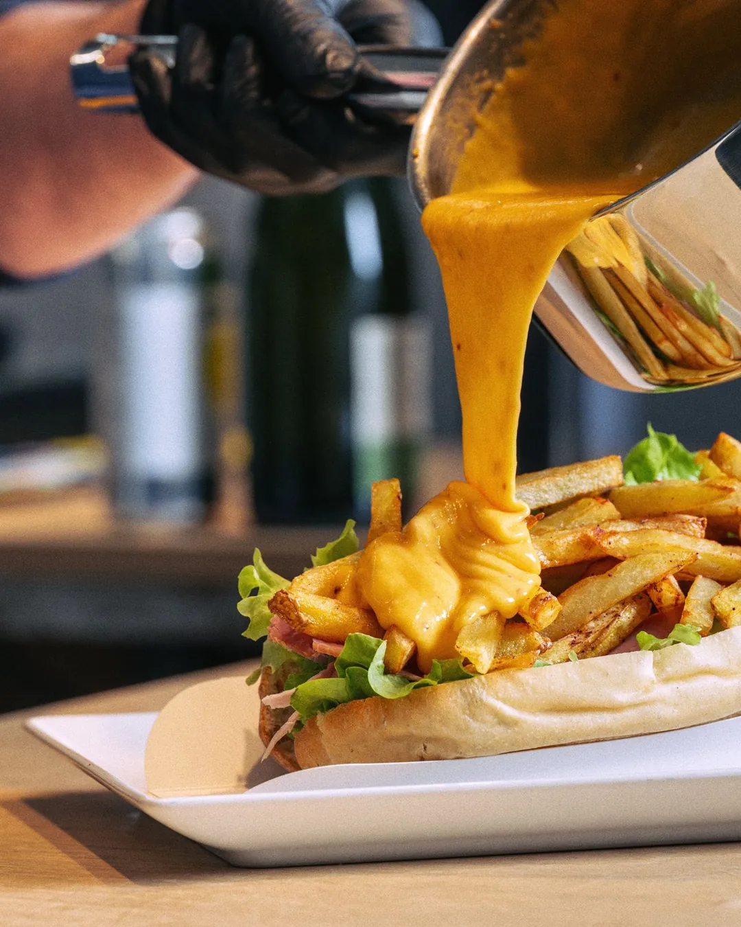 Sauce au fromage versée sur un sandwich et des frites