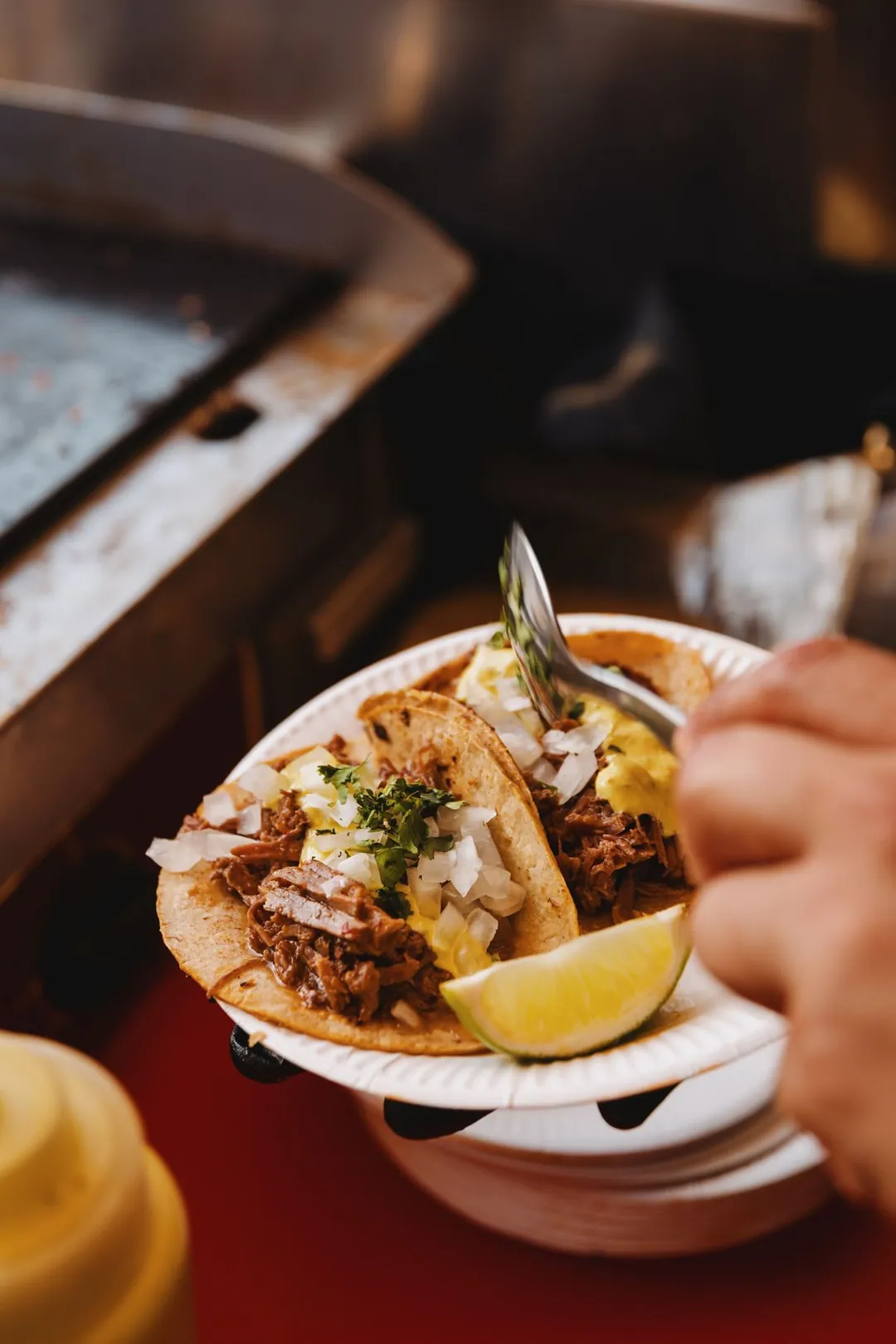 Tacos tenus dans une main, quartier de citron vert