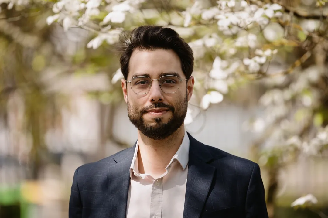 Thomas Bigot en veste, arbres en fleurs en arrière-plan