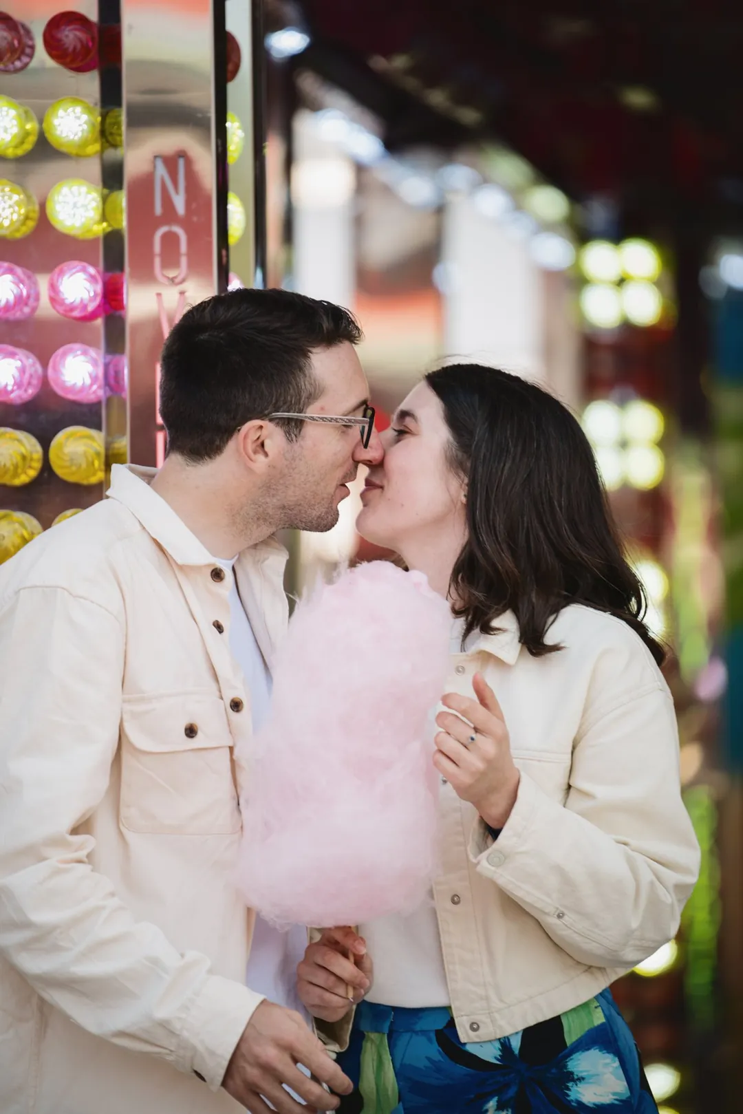 Un couple s'embrasse à la fête foraine, barbe à papa à la main