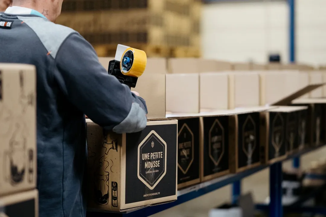 Un préparateur ferme des cartons sur une ligne d'expédition