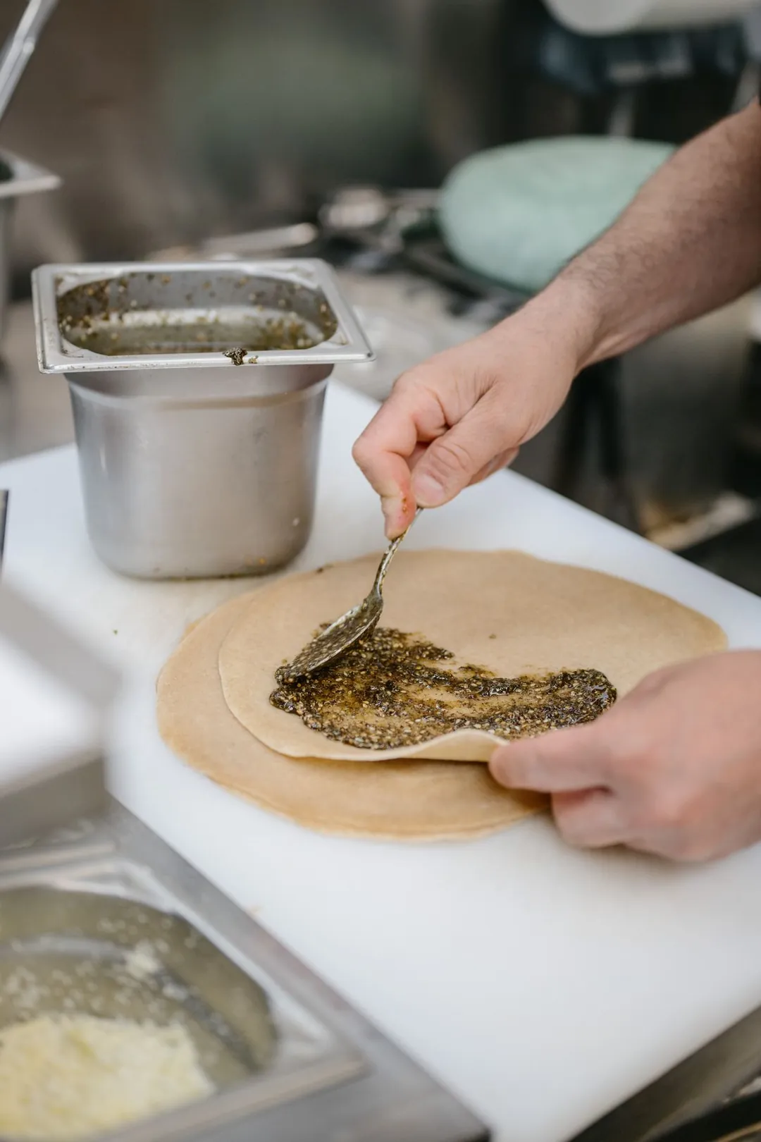 Une main étale une garniture sur une crêpe